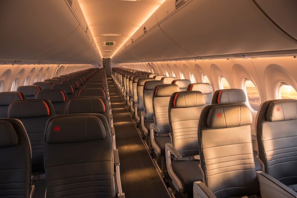 Air Canada Airbus A320 economy cabin looking down the aisle, 3-3 grey leather seating with red maple-leaf headrests
