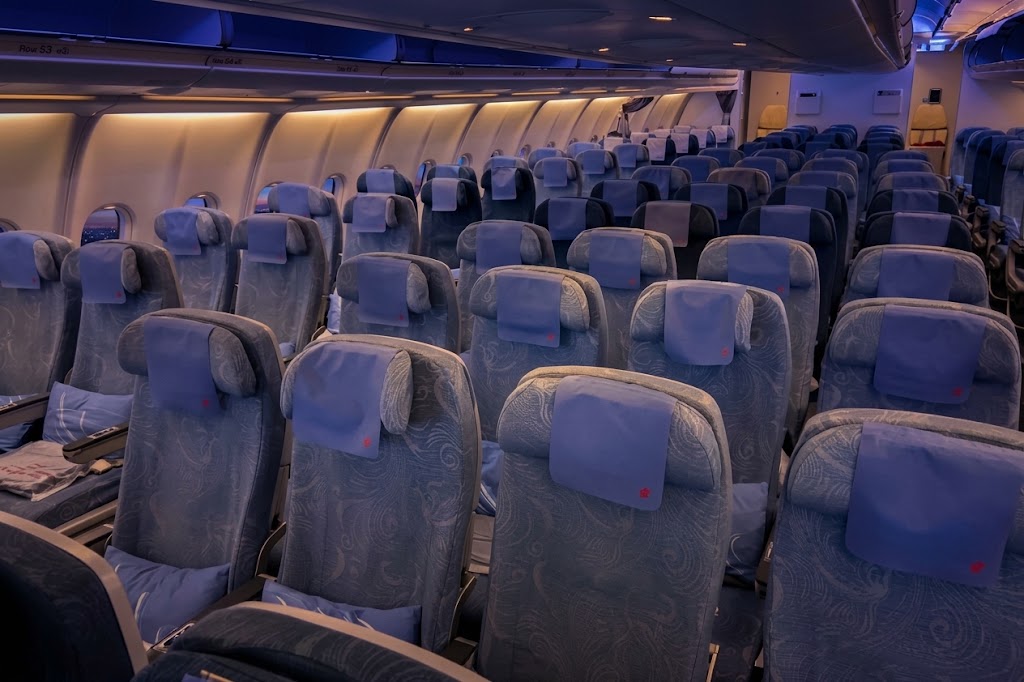 Air China Airbus A330-200 economy cabin looking aft under blue mood lighting, patterned grey-blue seats with blue headrest covers