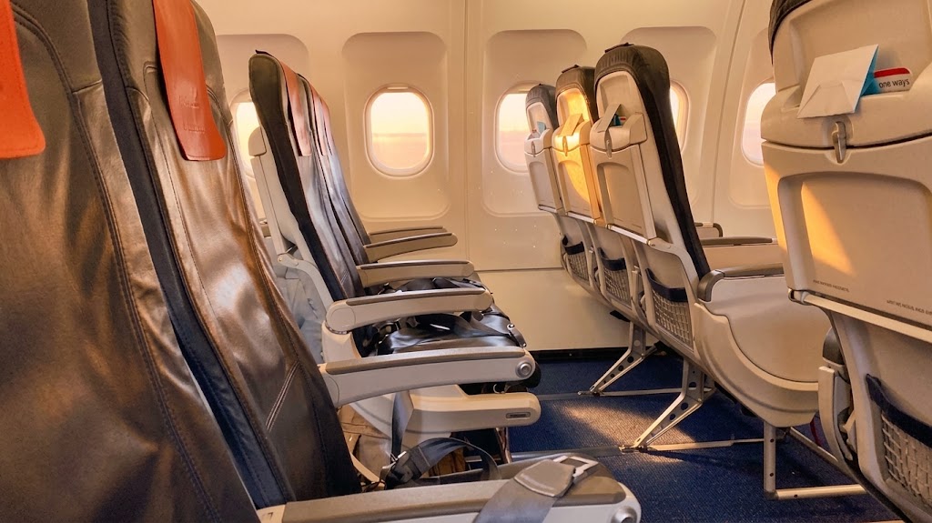 Brussels Airlines Airbus A319 cabin, a window-side row of slimline economy seats lit by low evening sun