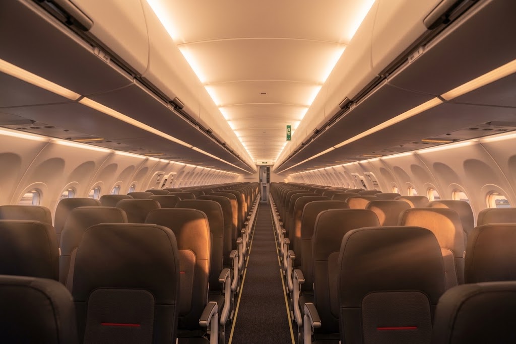 Brussels Airlines Airbus A320 economy cabin, 3-3 charcoal seats with a red accent stripe under warm cabin lighting