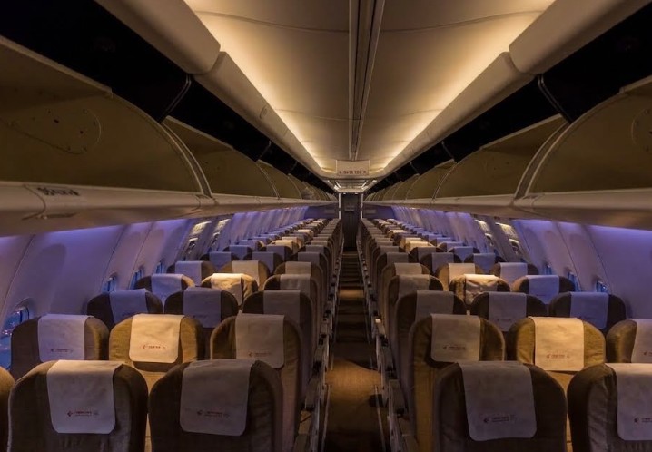 China Eastern Boeing 737-800 economy cabin looking aft down the aisle, three-abreast seating each side with cream headrest covers
