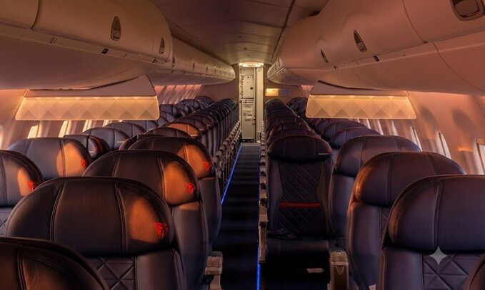 Delta Embraer 175 cabin at sunset with dark grey leather seats and the Delta widget on the headrests