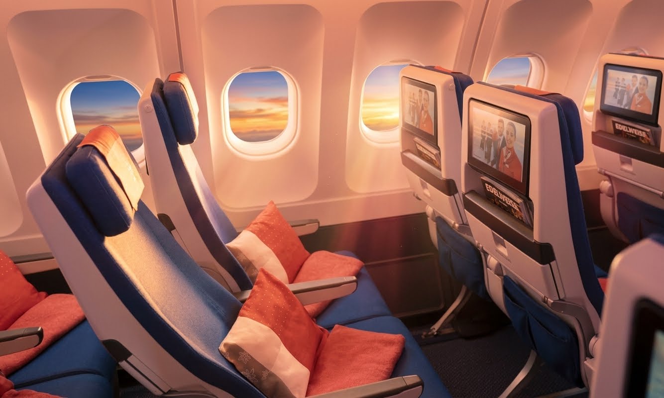 Edelweiss economy cabin with blue seats, seatback screens and red cushions
