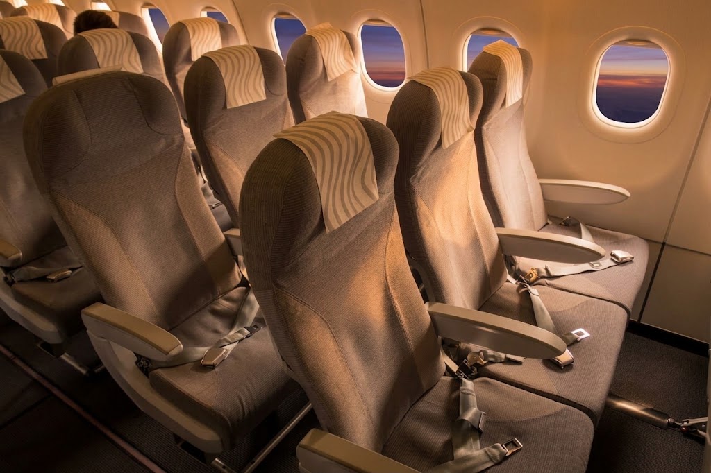 Finnair Airbus A321 economy cabin, three-three rows of grey slimline seats with tray tables down and sunset light through the windows