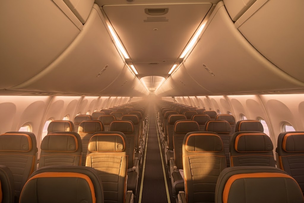 GOL Boeing 737-800 economy cabin looking down the aisle, three-three rows of grey seats with orange trim under warm cabin lighting