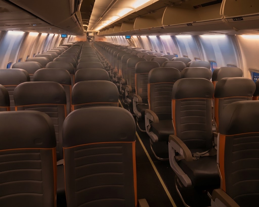 GOL Boeing 737 MAX 8 economy cabin looking down the aisle over three-three rows of grey seats with orange trim