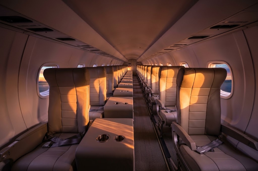 JSX jet cabin with single leather seats either side of the aisle and side tables with cupholders