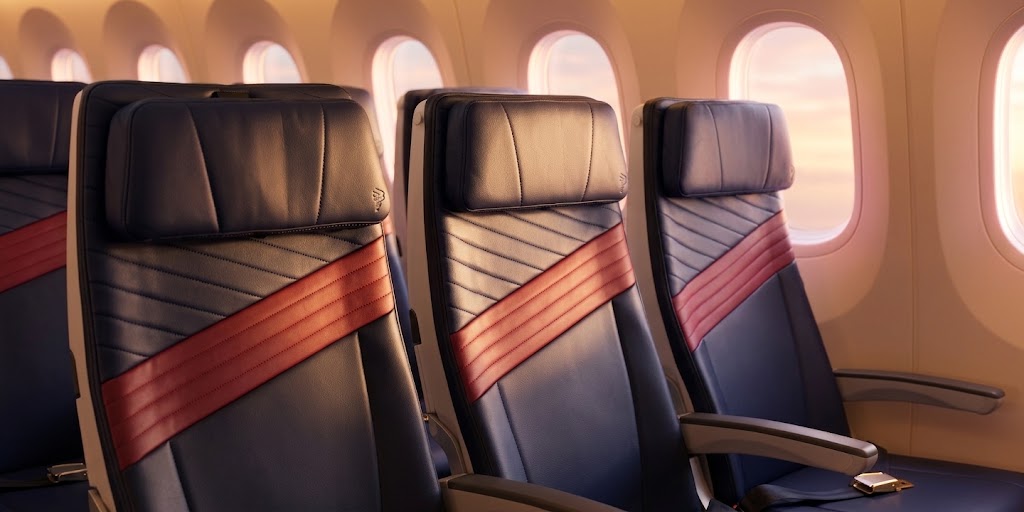 LATAM Boeing 787-8 economy seats in navy leather with a red diagonal band, beside the Dreamliner window line