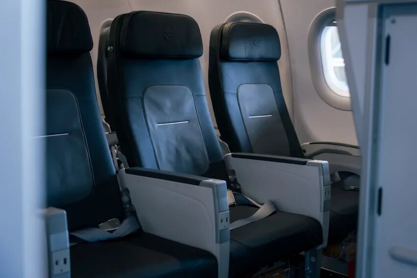 Lufthansa A320 economy cabin with dark grey leather seats and the crane logo on the headrests
