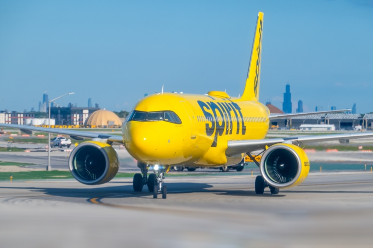 Spirit Airlines yellow Airbus A320 taxiing at Chicago O'Hare with the Chicago skyline behind