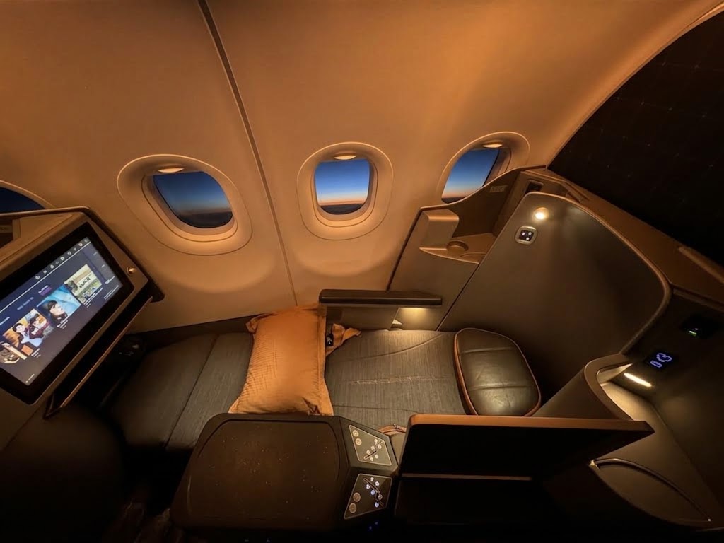 STARLUX Airlines business class seat in the lie-flat position, with a large seatback screen, side console and ambient cabin lighting