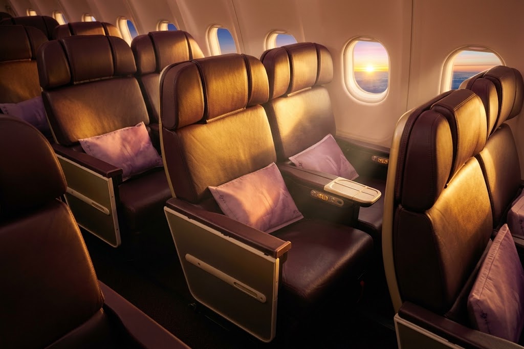 Thai Airways A330-300 cabin at sunset, purple and brown leather recliners with orchid-print cushions beside the windows