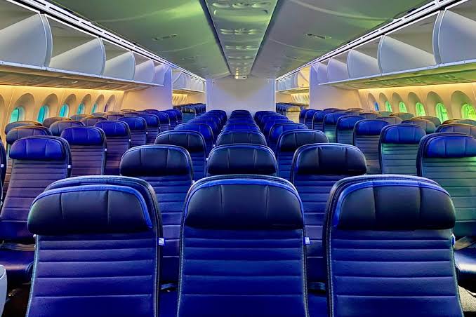 United Airlines Boeing 787 economy cabin, 3-3-3 blue seats looking forward under the 787 window lighting