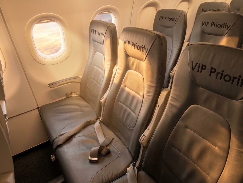Viva Aerobus economy cabin, grey leather seats with VIP Priority headrest covers beside the window at sunset
