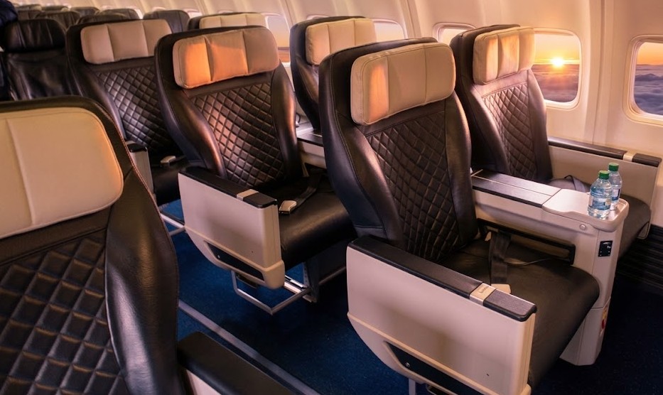 WestJet Boeing 737 Premium cabin, 2-2 black leather recliners with cream headrests beside the window at sunset