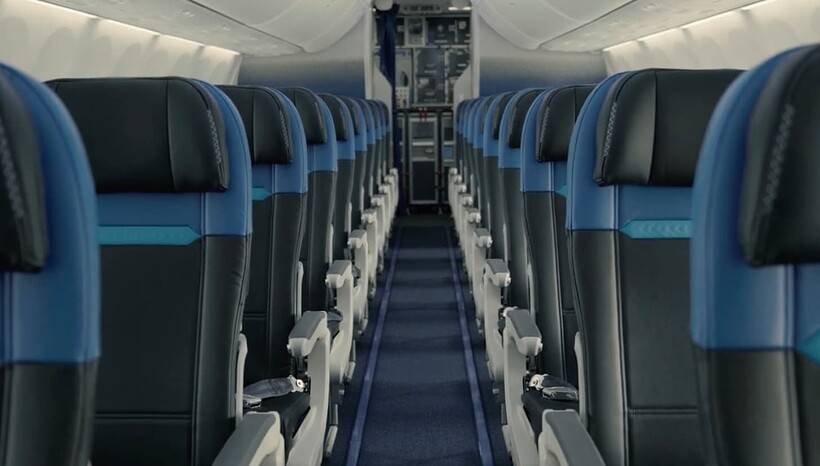 WestJet 737 economy cabin with blue-and-black 3-3 seating and no seatback screens