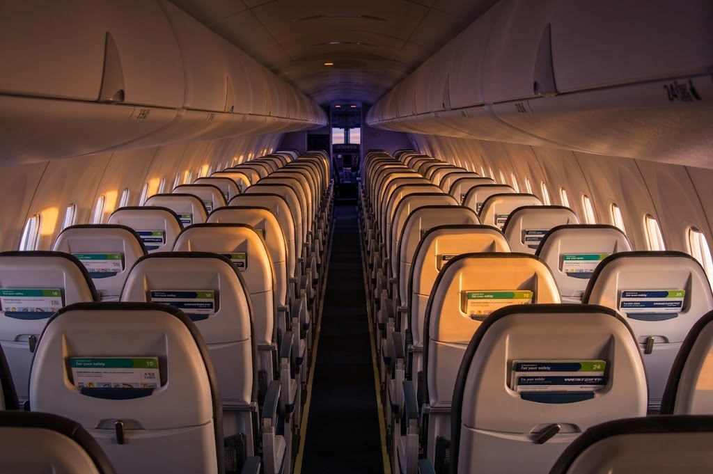 WestJet Encore Dash 8-400 cabin looking forward, 2-2 seating with WestJet safety cards in the seat pockets and no seatback screens