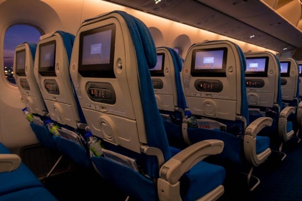 XiamenAir 787-9 economy seatbacks with screens beside a Dreamliner window at dusk