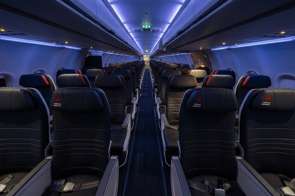 Air Canada Airbus A321 economy cabin with dark blue leather seats under blue mood lighting