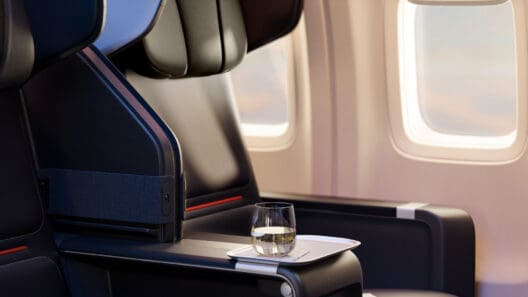 Delta Boeing 757-300 First Class recliner seat by the window with white tray and drink