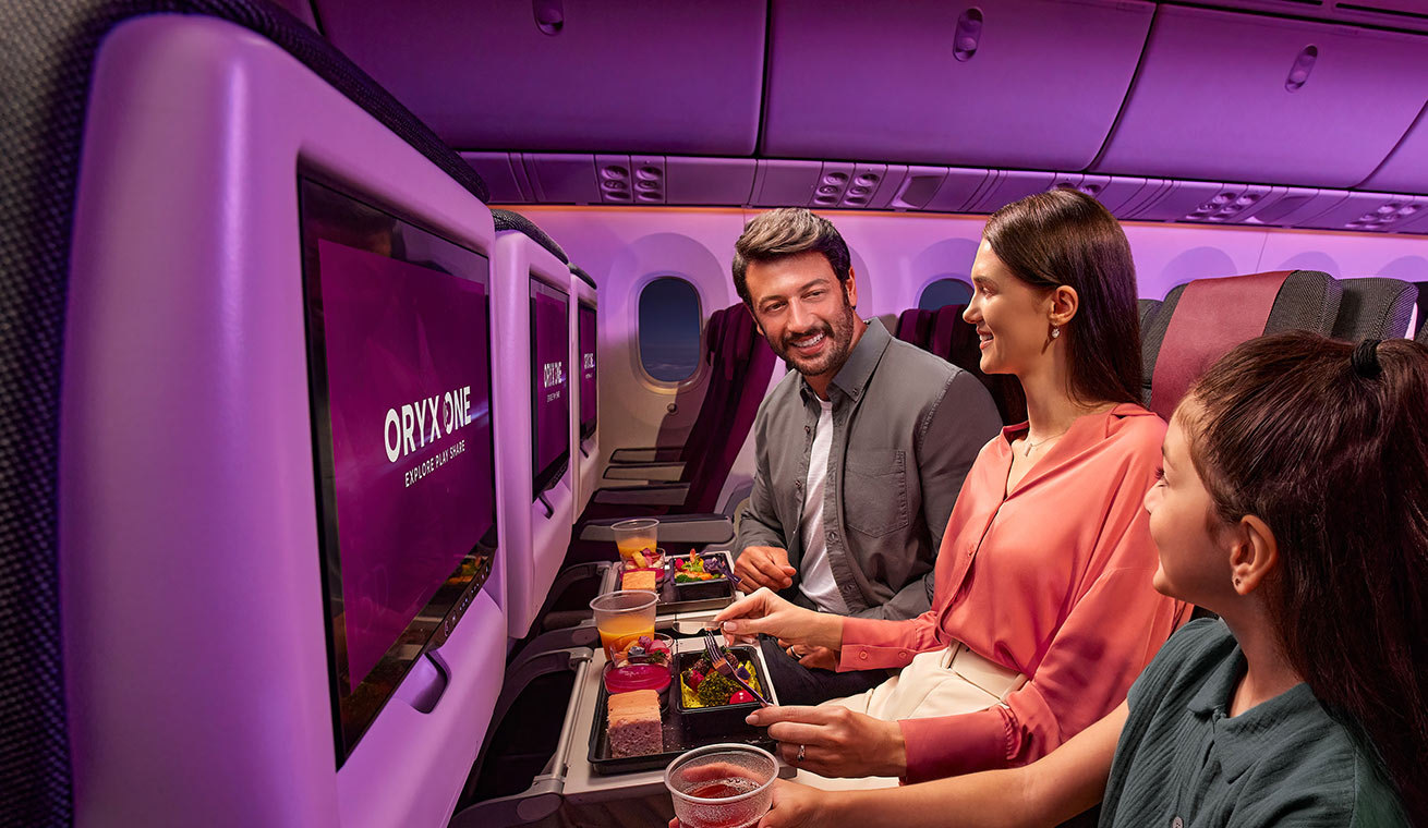 Family enjoying meal service together on a Qatar Airways flight with Oryx One entertainment